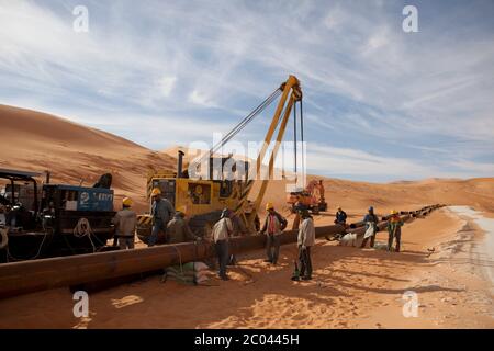 Les soudeurs se préparent à réunir un pipeline d'exportation dans le désert du Sahara pour transporter le pétrole de ses engins de forage vers la côte. Banque D'Images