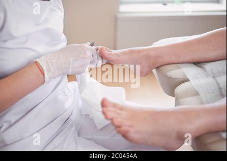 Procédure médicale professionnelle de pédicure gros plan à l'aide d'un coupe-ongles. Patient visitant le podiatre chiropodiste. Soins des pieds dans le salon DE SPA. Banque D'Images