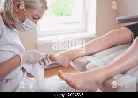 Procédure médicale professionnelle de pédicure gros plan à l'aide d'un coupe-ongles. Patient visitant le podiatre chiropodiste. Soins des pieds dans le salon DE SPA. Banque D'Images