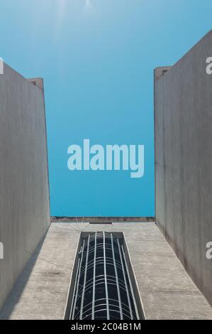 Vue à angle bas d'un escalier d'évacuation de feu externe en spirale d'un bâtiment avec ciel bleu. Banque D'Images