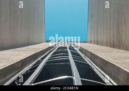 Vue à angle bas d'un escalier d'évacuation de feu externe en spirale d'un bâtiment avec ciel bleu. Banque D'Images