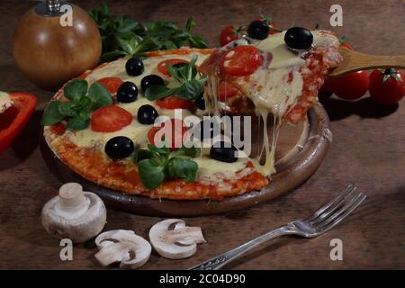 Piece de pizza sur une pelle en bois Banque D'Images