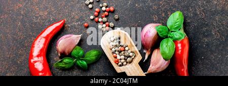 Arrière-plan alimentaire avec espace de copie. Sélection d'épices herbes. Ingrédients pour la cuisson. Poivre rouge, ail, feuilles de basilic, cornes de poivre sur conc. De pierre sombre Banque D'Images