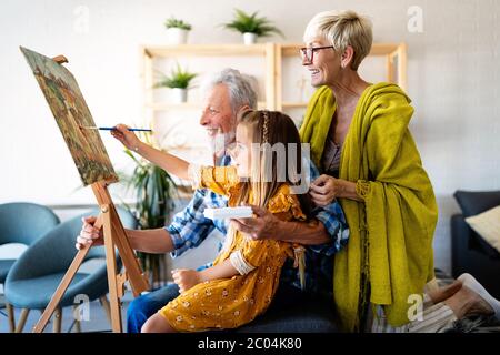 Joyeux grand-parents souriants et peinture de petit-enfant ensemble. Famille, génération, concept de bonheur Banque D'Images