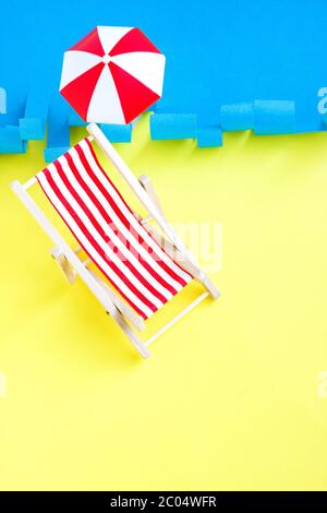 Chaise de terrasse rouge à rayures près de la mer. Fauteuil inclinable sur fond bleu et jaune. Concept repos d'été. Vacances. Banque D'Images