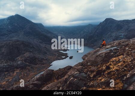 Concept de mode de vie de sport de voyage. Homme au-dessus d'un nuage brumeux, paysage vallonné le matin. Vue sur la chaîne de montagnes de Cullin, vue sur un lac de l'île de S. Banque D'Images