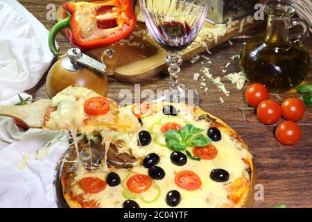 Vin rouge dans un verre transparent et une pizza sur une pelle en bois Banque D'Images