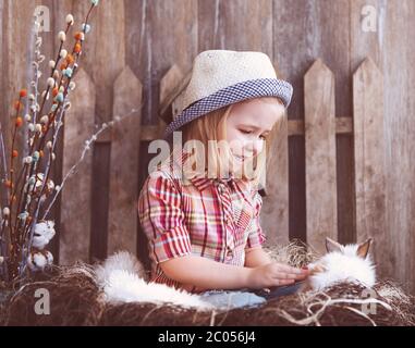 Portrait d'une adorable petite fille et d'un petit lapin blanc près du fond en bois Banque D'Images