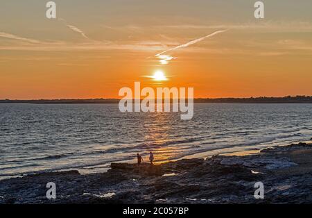 Coucher de soleil sur Porthcawl sur la côte sud du pays de Galles. Photographie prise d'Ogmore par Sea Beach en soirée d'été. Deux personnes sur la mer. Banque D'Images