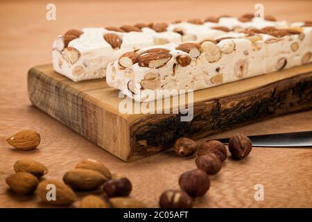Blocs de Turron avec amandes et noisettes sur planche à découper, sur table en bois, gros plan