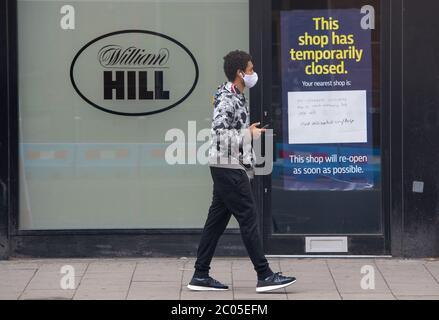 Un homme passe devant une succursale fermée des bookmakers William Hill à Waterloo, Londres, après l'introduction de mesures pour sortir l'Angleterre du confinement. Banque D'Images