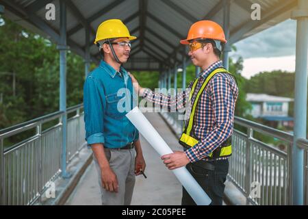 Deux ingénieurs se tiennent à la main sur le pont Banque D'Images