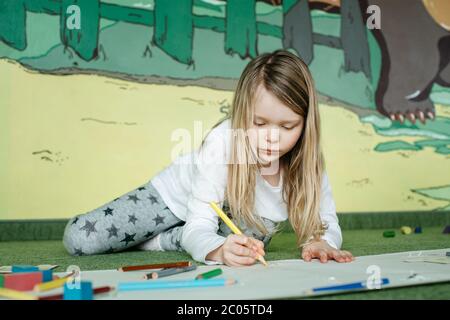 Fille couché sur le sol et dessin d'une photo avec des crayons de couleur Banque D'Images