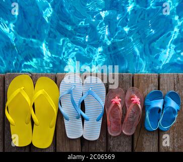 Les tongs aux couleurs vives sur fond de bois près de la piscine Banque D'Images