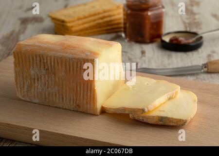 Pièce et tranches de fromage tdc traditionnel italien Taleggio en gros plan sur une planche à découper Banque D'Images