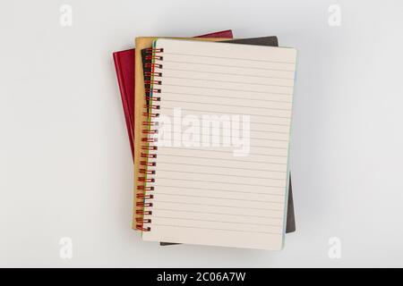 une pile de plusieurs carnets d'école en spirale se trouve sur une table blanche avec un crayon, concept de bureau Banque D'Images