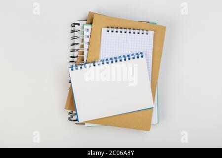 une pile de plusieurs carnets d'école en spirale se trouve sur une table blanche avec un crayon, concept de bureau Banque D'Images