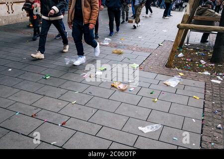 Les gens qui marchent parmi les sacs de plastique vides, les emballages de chocolat, les décorations de festival et autres déchets après le défilé traditionnel de carnaval d'hiver. Banque D'Images