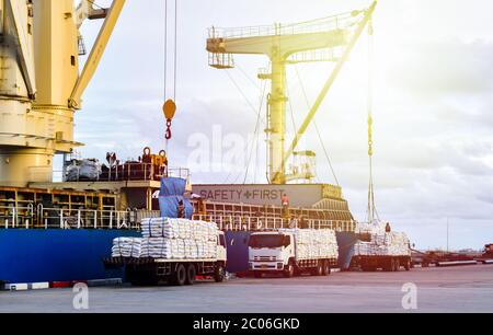 Sacs de sucre produit navire activités de chargement, navire grue soulever le sac de sucre blanc de la charge de camion dans la trappe de navire. Banque D'Images