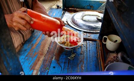 les vendeurs de nouilles de poulet de rue préparent des menus alimentaires sur le chariot. Pas de mise au point, de bruit et de mise au point sélective floue Banque D'Images