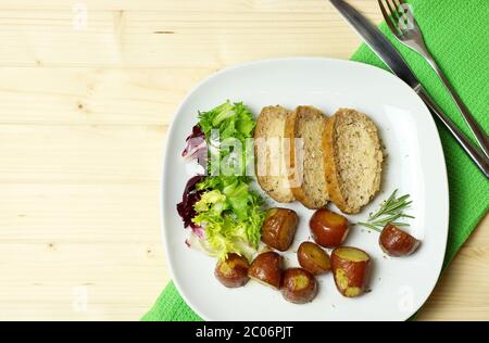 Concept de la cuisine italienne. Tranches de délicieux pain de dinde cuit maison moulu, pommes de terre rouges et salade fraîche sur table en bois. Vue de dessus. Pose à plat. Banque D'Images