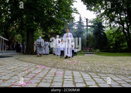 Un serveur d'autel tenant une énorme croix à la paroisse de la Sainte Vierge Marie de Czestochowa à la rue Kochanowskiego pendant la procession.la Fête du corps et du sang du Christ (Corpus Christi) Est une fête dédiée à la vénération du corps et du sang du Christ, dans laquelle le pain et le vin sont transformés pendant l'Eucharistie selon la foi chrétienne. Selon la tradition, une procession solennelle est organisée dans les rues de l'Église catholique ce jour-là. En Pologne, ce jour est un jour férié. Cette année, de nombreux participants au cortège portaient des masques médicaux, dont alt Banque D'Images