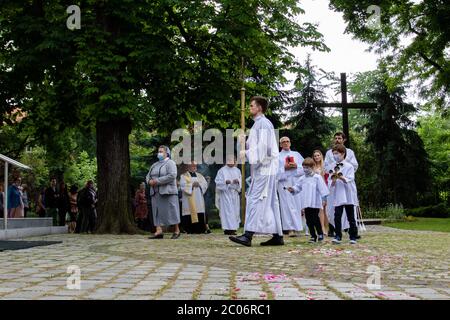 Un serveur d'autel tenant une énorme croix à la paroisse de la Sainte Vierge Marie de Czestochowa à la rue Kochanowskiego pendant la procession.la Fête du corps et du sang du Christ (Corpus Christi) Est une fête dédiée à la vénération du corps et du sang du Christ, dans laquelle le pain et le vin sont transformés pendant l'Eucharistie selon la foi chrétienne. Selon la tradition, une procession solennelle est organisée dans les rues de l'Église catholique ce jour-là. En Pologne, ce jour est un jour férié. Cette année, de nombreux participants au cortège portaient des masques médicaux, dont alt Banque D'Images