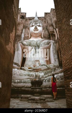 Une jolie petite fille touristique debout devant la statue du Grand Bouddha au temple Wat si CHUM à Sukhotai en Thaïlande Banque D'Images
