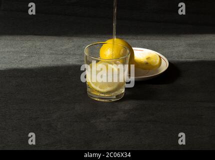 Dans un verre avec des quartiers de citron, on a versé de l'eau gazéifiée dans une bouteille Banque D'Images