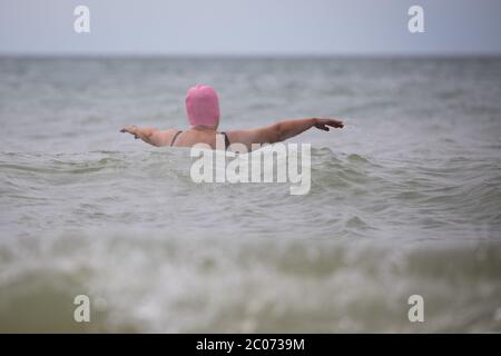 11 juin 2020, Schleswig-Holstein, Westerland/Sylt: Une femme avec un bonnet de bain rose nage dans la mer du Nord sur la plage de Westerland sur Sylt. Photo: Christian Charisius/dpa