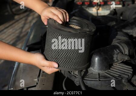 Auto mécanicien tenant un filtre à air sale sur un moteur de voiture pour le nettoyage Banque D'Images