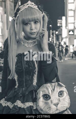 Une fille japonaise non identifiée en costume noir et cheveux blonds marchant à Harajuku à Tokyo Japon (exemple de cosplay japonais typique) Banque D'Images