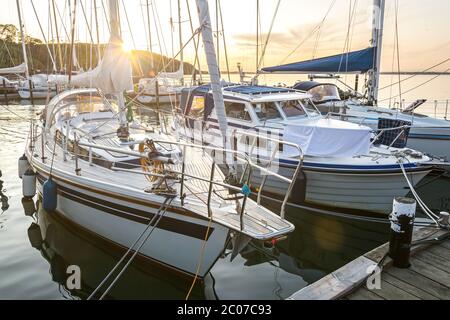 Bateaux à voile dans une marina pendant un beau coucher de soleil doré sur la mer Baltique Banque D'Images