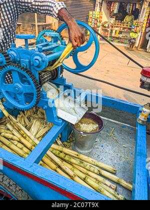 Street Side sugarcane Juice Maker, faisant le jus en écrasant les sucreries. Banque D'Images