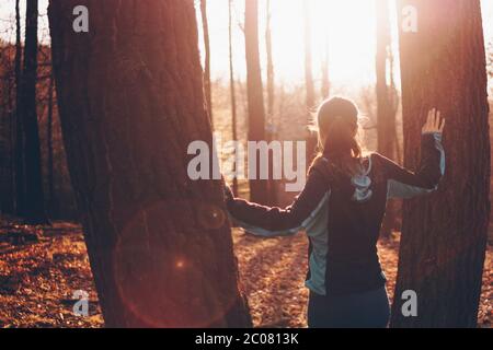 Belle scène d'une jeune femme debout entre deux arbres regardant le coucher du soleil Banque D'Images