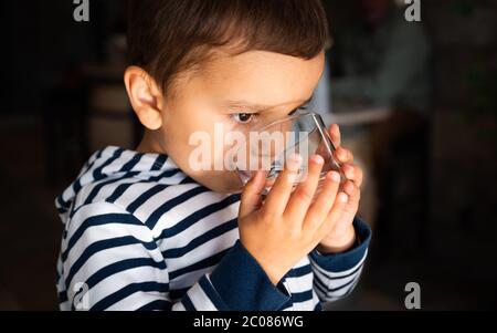 Un petit garçon boit de l'eau du verre Banque D'Images