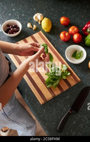 Anonyme femme suivant une recette en ligne préparant le dîner avec un ordinateur portable. Banque D'Images