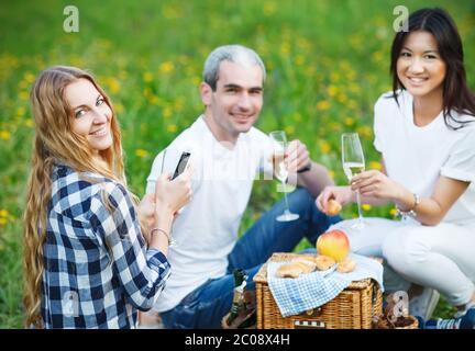 Des amis souriants et heureux buvant du champagne au pique-nique Banque D'Images