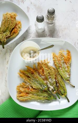 Concept des légumes. Fleurs de courgettes frites dans de la pâte et saupoudrées de parmesan sur fond clair. Vue de dessus. Banque D'Images