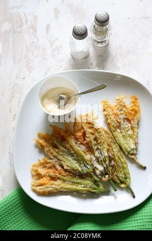 Concept des légumes. Fleurs de courgettes frites dans de la pâte et saupoudrées de parmesan sur fond clair. Vue de dessus. Banque D'Images