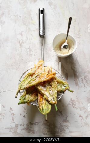 Concept des légumes. Fleurs de courgettes frites dans de la pâte et saupoudrées de parmesan sur fond clair. Vue de dessus. Banque D'Images