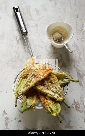 Concept des légumes. Fleurs de courgettes frites dans de la pâte et saupoudrées de parmesan sur fond clair. Vue de dessus. Banque D'Images