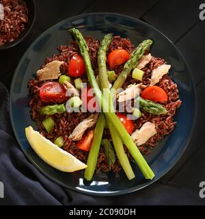 Concept d'alimentation saine. Salade fraîche avec riz rouge, thon, asperges, tomates et citron sur fond sombre. Vue de dessus. Banque D'Images