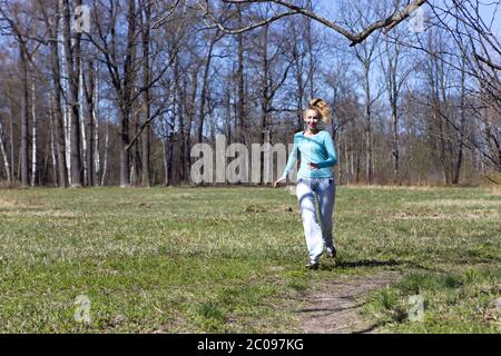 femme court sur la piste dans le bois de printemps Banque D'Images