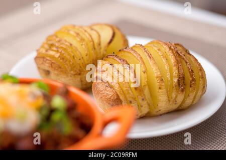 Accompagnement de pommes de terre hasselback cuites au four et grillées. Les pommes de terre Hasselback sont des quartiers de pommes de terre finement tranchés qui sont encore jointes au fond d'un Banque D'Images