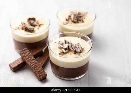 Mousse au chocolat sans cuisson et cheesecake avec garniture de chapelure de biscuits enrobées de chocolat. Dans des bols à dessert en verre transparent. Sur fond blanc. Banque D'Images