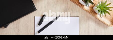 vue de dessus des plantes vertes, carnets noirs, papier blanc avec stylo sur une surface en bois, vue panoramique Banque D'Images