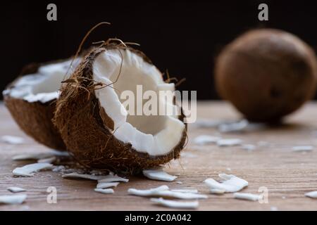 foyer sélectif de noix de coco fraîches savoureuses et des flocons sur table en bois isolée sur noir Banque D'Images