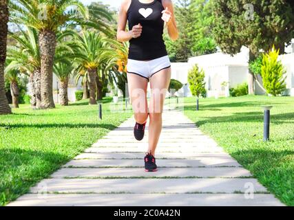 Pieds d'exécution sur Road Runner dans le parc. Femme sunrise fitness workout jog welness concept Banque D'Images