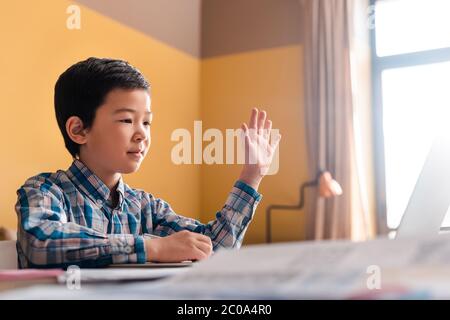 un garçon asiatique étudie en ligne avec un ordinateur portable à la maison pendant la quarantaine